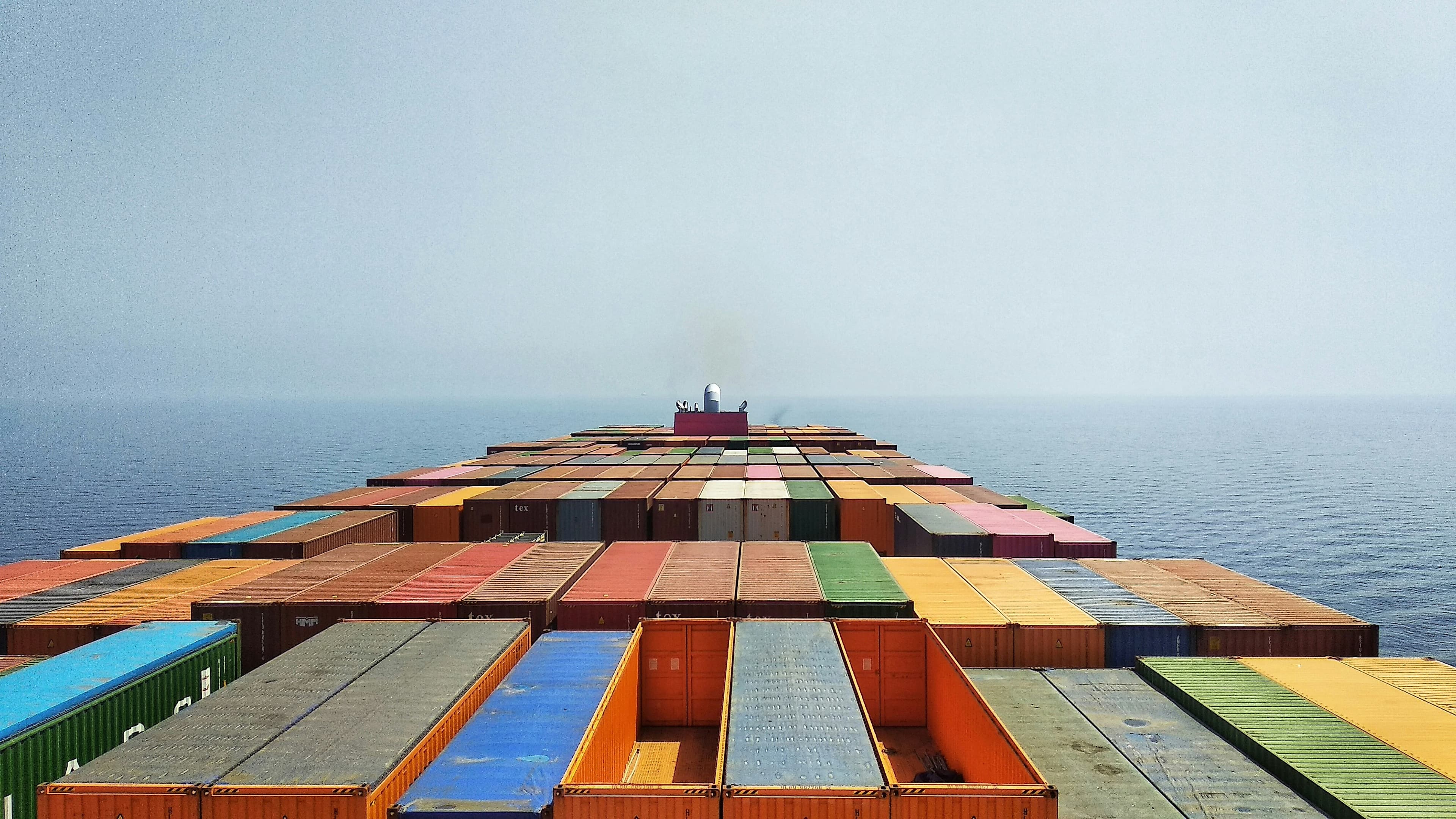View from a container ship’s bridge across stacked containers toward the horizon